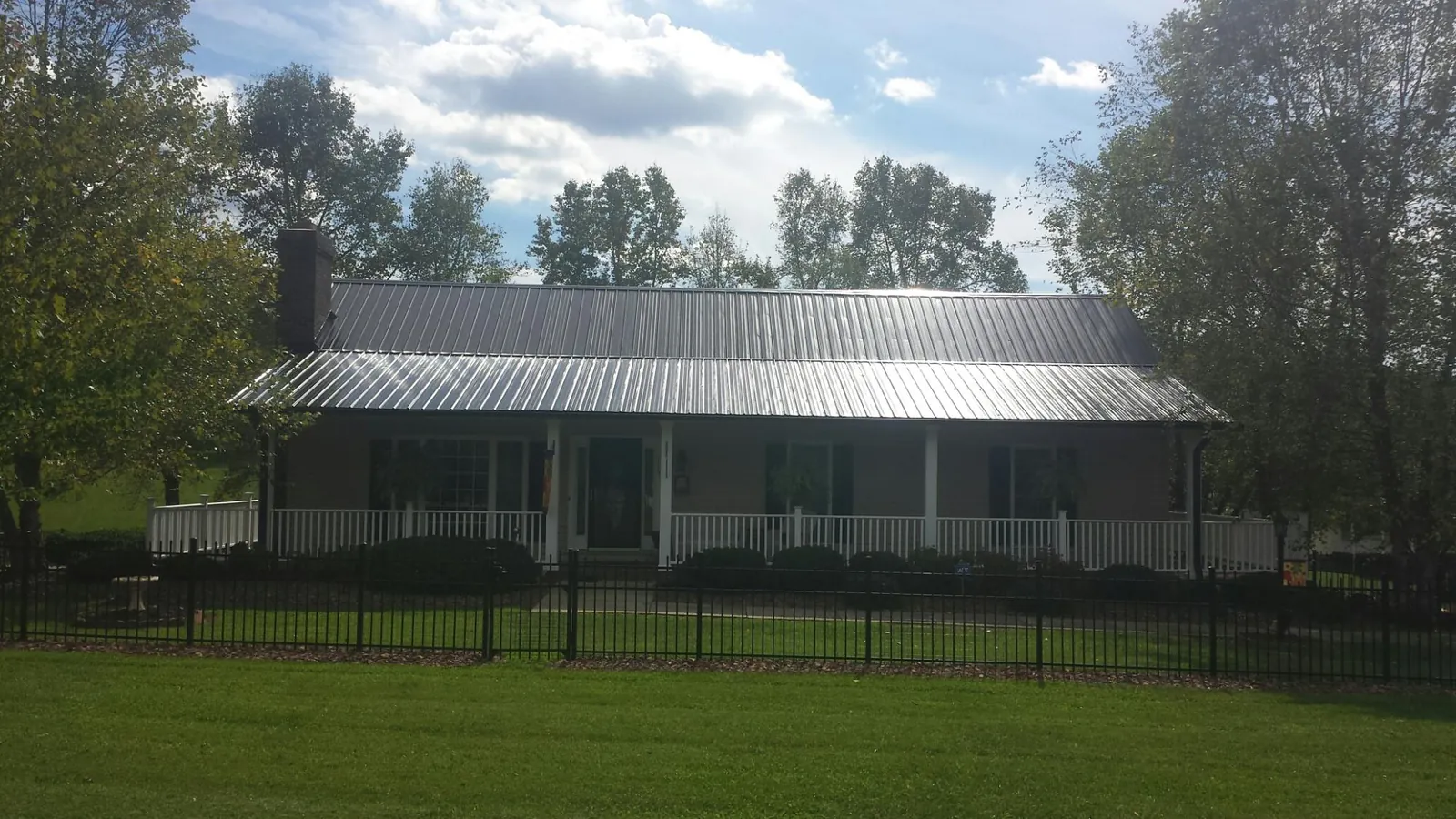 Gray metal roof on a brick ranch with a full width front porch — Gutter Guard Installation work by our crew in Thornton