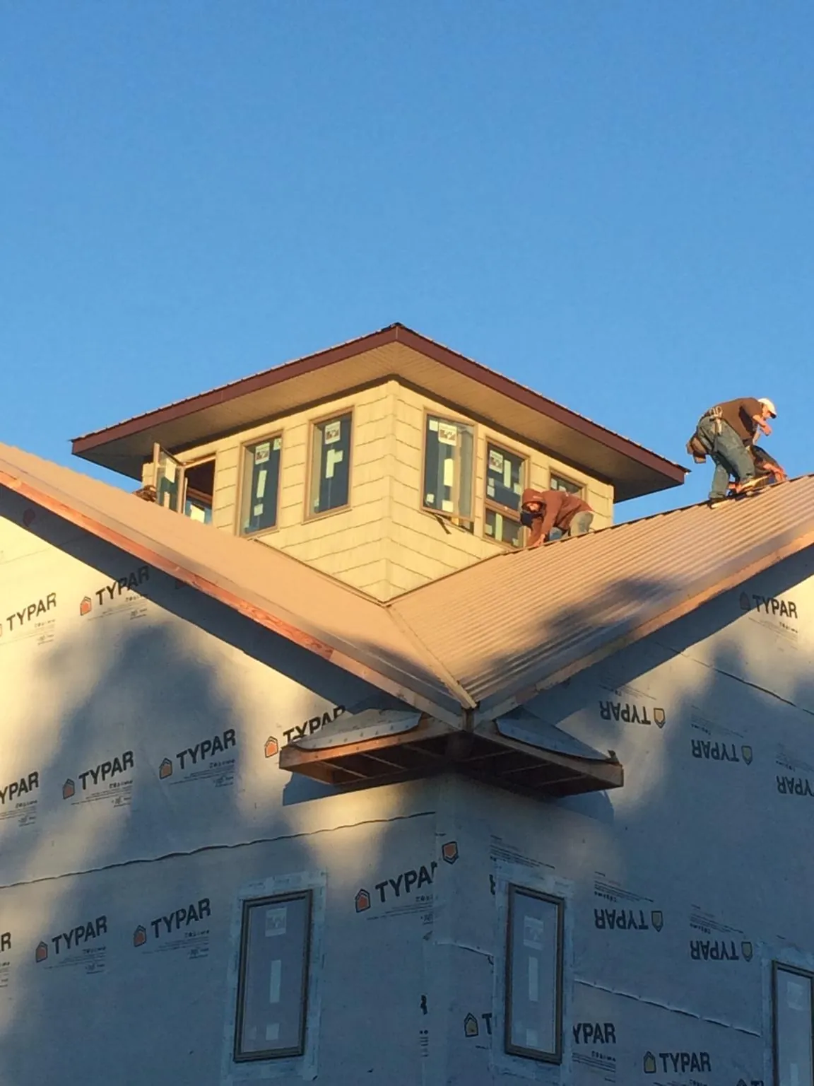 Roofers working around a rooftop cupola on a new metal roof at sunset — Roof Waterproofing in Thornton by Roofing Brothers